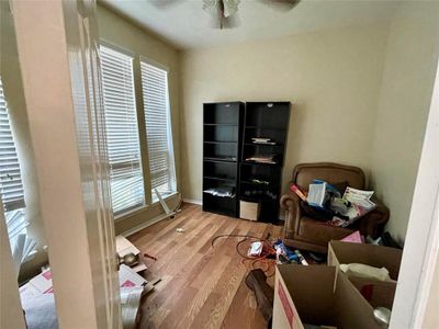 Located just off the foyer, a spacious study behind double doors provides a generous area for focused work or study. It features a high ceiling with a ceiling fan, elegant wood-like flooring, and large windows. | Image 3