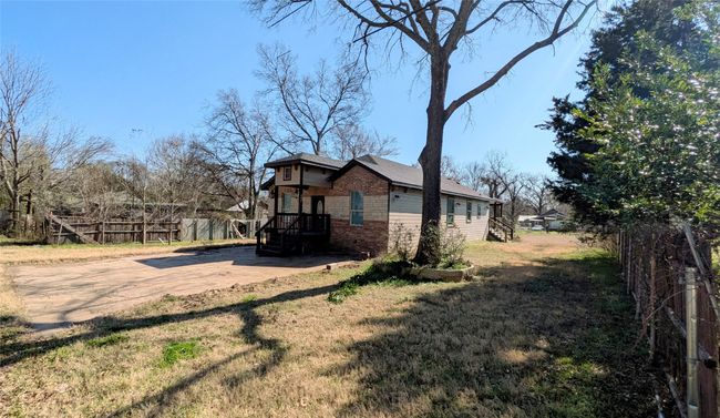 View of property exterior featuring brick siding, a lawn, and fence | Image 19