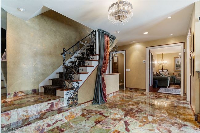 As you enter into the home you are welcomed by this beautiful marble flooring. The staircase ribbon railing leading to the spacious second floor. Notice the room that is currently being used as another living room. It is spacious for living room, office or den. | Image 47