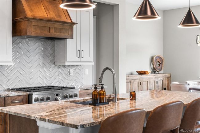 Chef's dream kitchen with upgraded pendant lighting, GE Cafe appliances (6-burner gas range, wall oven/airfryer, French door refrigerator) custom range hood and herringbone tile backsplash. Large granite island soft-close maple cabinets will roll-out drawers and large pantry. | Image 15