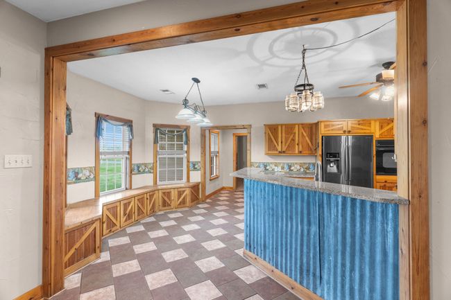 Kitchen with hanging light fixtures, stainless steel refrigerator with ice dispenser, a ceiling fan, black oven, and tile patterned floors | Image 18