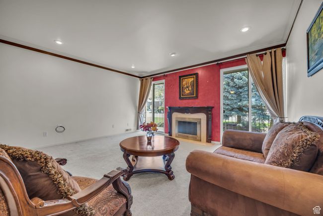 Living area featuring a wealth of natural light, a fireplace, ornamental molding, and carpet floors | Image 11