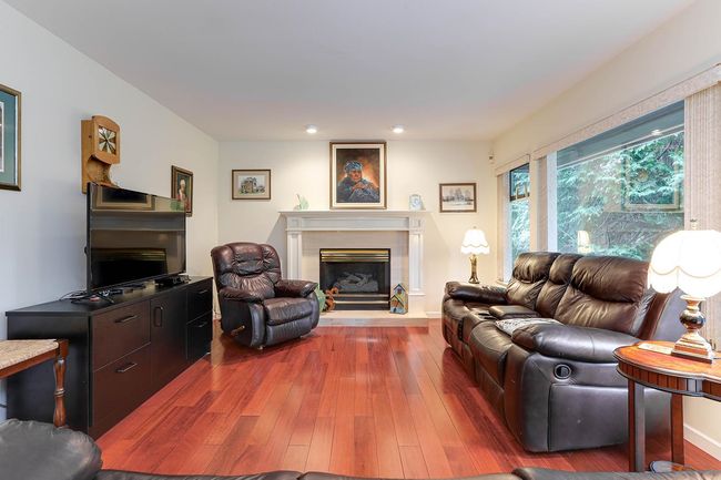 Living room featuring baseboards, a fireplace with raised hearth, wood finished floors, and recessed lighting | Image 16