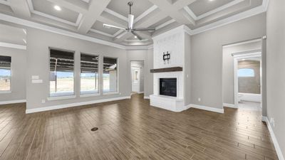 Living room with a fireplace, coffered ceiling, beamed ceiling, ceiling fan, and dark hardwood / wood-style floors | Image 3