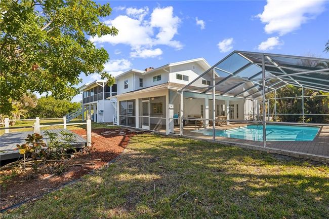 Rear view of property with a lawn, an outdoor pool, a sunroom, stairway, and a patio | Image 34