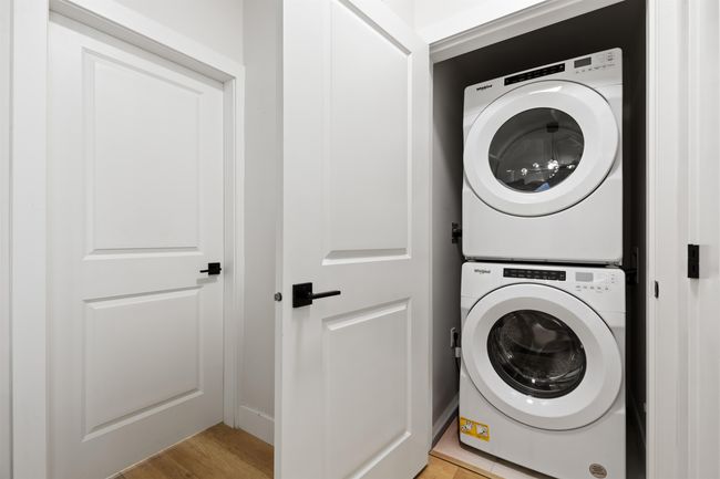 Clothes washing area featuring light wood-style floors, stacked washer and dryer, and laundry area | Image 16
