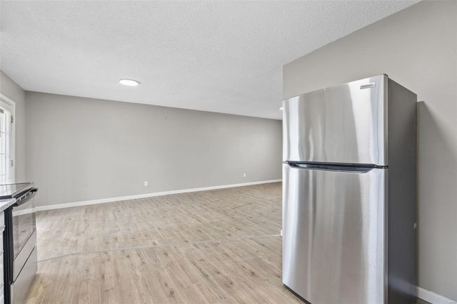 Kitchen with freestanding refrigerator, a textured ceiling, baseboards, and light wood-type flooring | Image 11