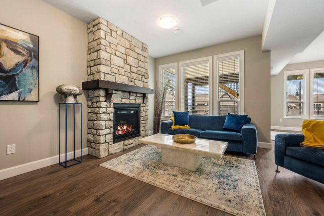 Living area with a stone fireplace, baseboards, and wood finished floors | Image 31