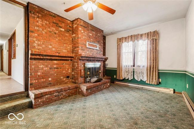 unfurnished living room featuring baseboard heating, a fireplace, ceiling fan, carpet flooring, and a baseboard heating unit | Image 14