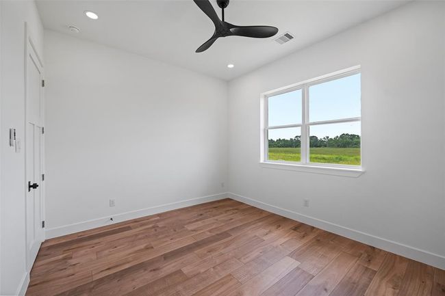 This inviting third bedroom features sleek hardwood floors, ample natural light, and a convenient Jack & Jill bathroom, perfect for guests or family. | Image 43
