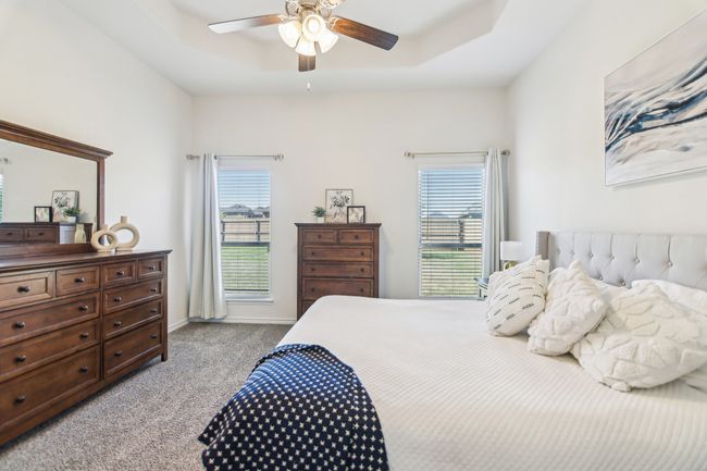Bedroom featuring a raised ceiling, light carpet, ceiling fan, and baseboards | Image 17