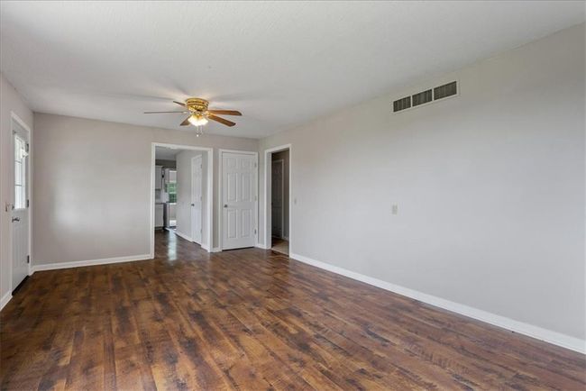 Empty room with wood finished rental or AIRBNBfloors, baseboards, ceiling fan, and visible vents | Image 51