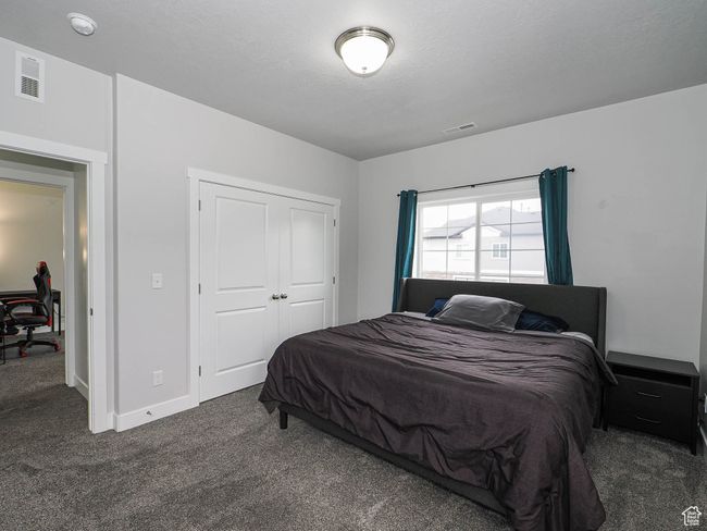 Bedroom with carpet flooring, a textured ceiling, a closet, and visible vents | Image 19