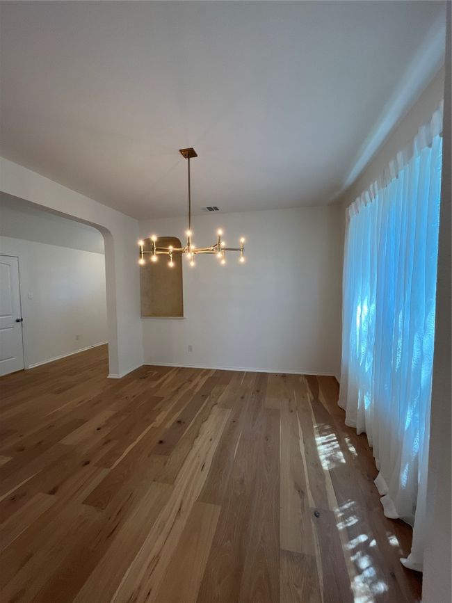 Unfurnished dining area with arched walkways, visible vents, wood finished floors, and a notable chandelier | Image 5