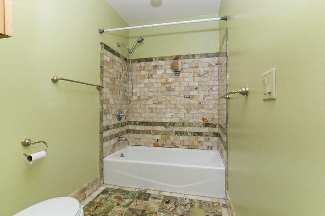 Full bathroom featuring shower / bathtub combination, toilet, tile patterned flooring, and baseboards | Image 25