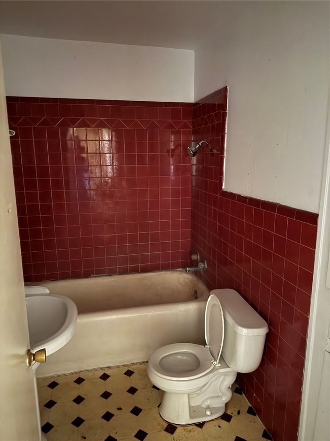 Full bath featuring tile walls, tile patterned floors, and washtub / shower combination | Image 16