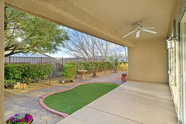 View of covered patio with a fenced backyard, retractable awning and ceiling fan | Image 17