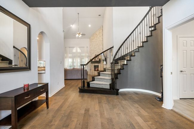 Foyer with stairs, high vaulted ceiling, wood finished floors, a ceiling fan, and arched walkways | Image 7
