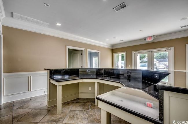 Kitchen featuring ornamental molding, dark countertops, wainscoting, stone finish floors, and french doors | Image 7