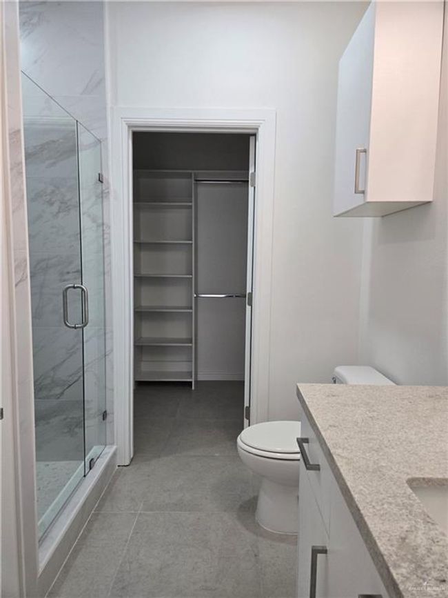 Full bathroom featuring vanity, a stall shower, a walk in closet, and tile patterned flooring | Image 7