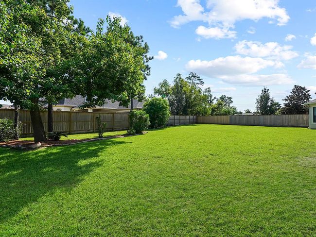Spacious covered patio with a fan, offering a stunning view of the expansive backyard! Plenty of space to create your own backyard oasis with a pool! | Image 48