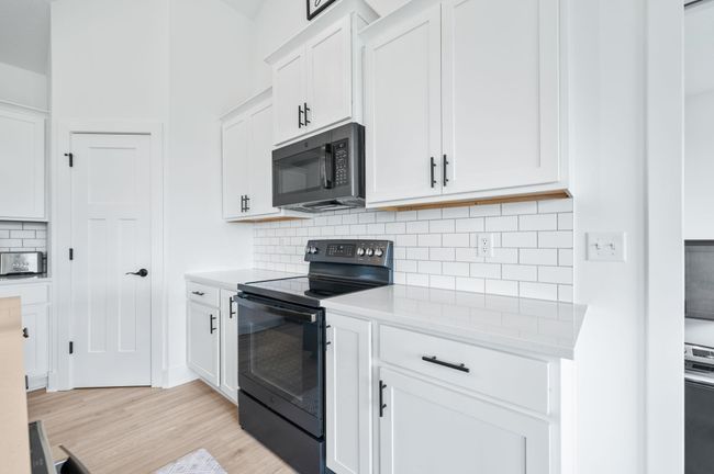 Kitchen featuring black appliances, light countertops, light wood-style floors, and white cabinets | Image 11