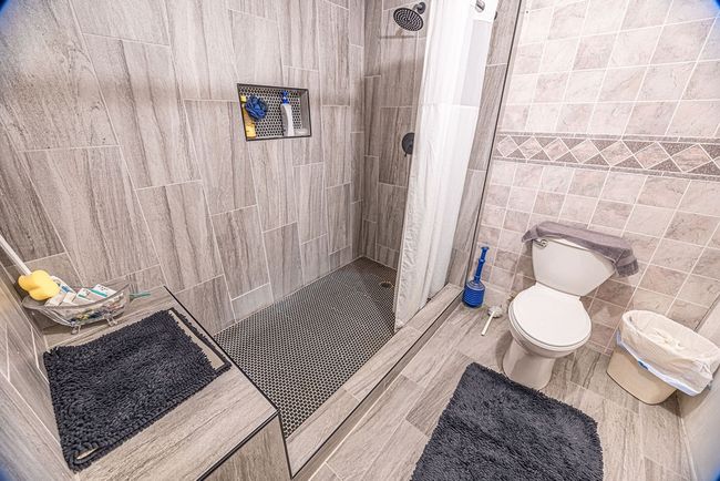 Bathroom featuring tile patterned flooring, a shower with curtain, toilet, and tile walls | Image 36