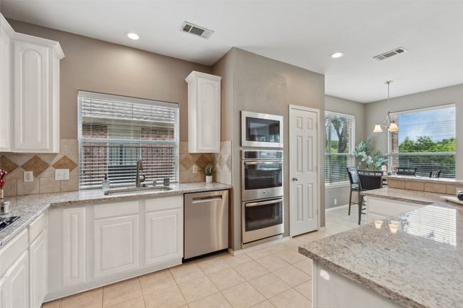 * Virtual rendering of kitchen cabinets painted white. Kitchen with appliances with stainless steel finishes, decorative backsplash, light tile patterned floors, white cabinetry, and recessed lighting | Image 5