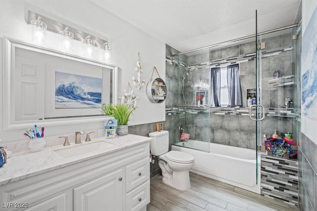 Full bathroom featuring enclosed tub / shower combo, toilet, and vanity | Image 16