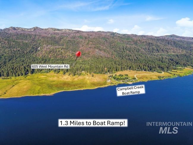 Drone / aerial view of a heavily wooded area and a water and mountain view | Image 13