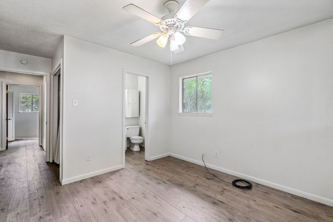 Unfurnished bedroom featuring wood finished floors, ensuite bath, and a ceiling fan | Image 11