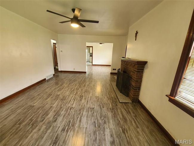 Unfurnished living room featuring dark wood-style flooring, a ceiling fan, and a fireplace | Image 6