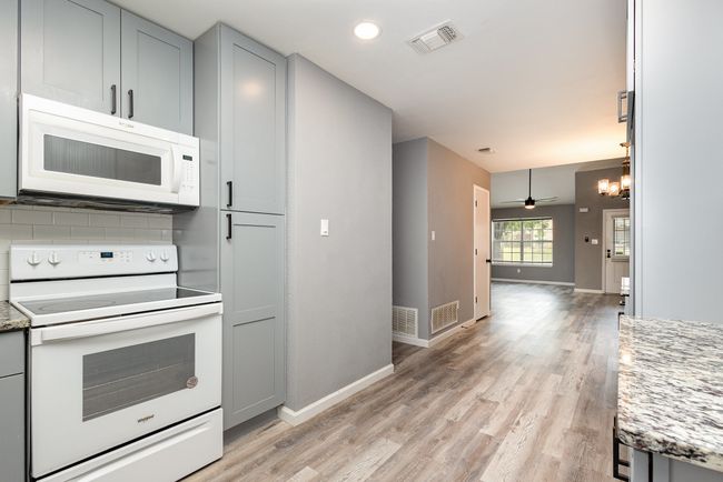 Kitchen featuring white appliances, light wood-type flooring, gray cabinetry, baseboards, and decorative backsplash | Image 14