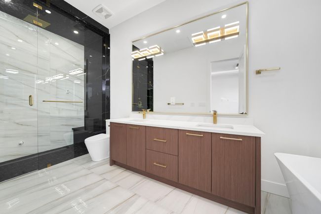 Full bath featuring toilet, double vanity, a marble finish shower, a freestanding tub, and marble finish flooring | Image 17