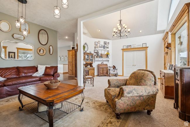 Living room with a chandelier, carpet, lofted ceiling, and baseboards | Image 10