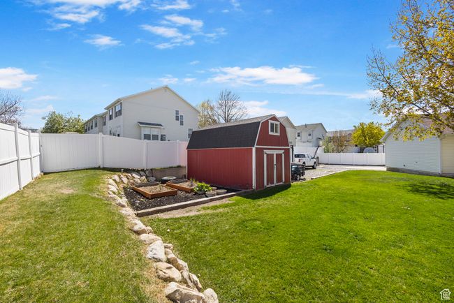 View of yard featuring a fenced backyard, a garden, a residential view, a shed, and an outbuilding | Image 35