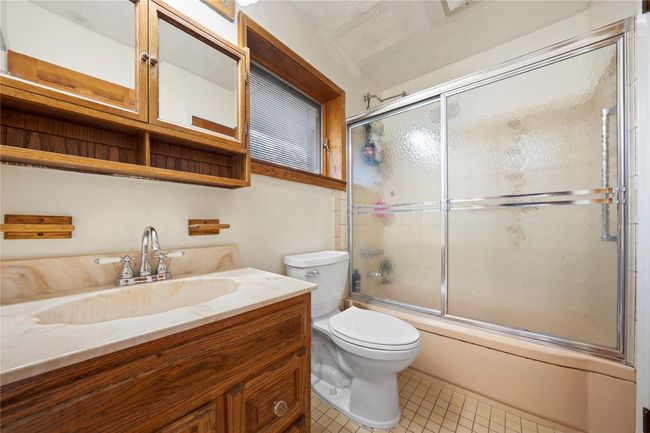 Bathroom with combined bath / shower with glass door, tile patterned floors, vanity, and toilet | Image 7