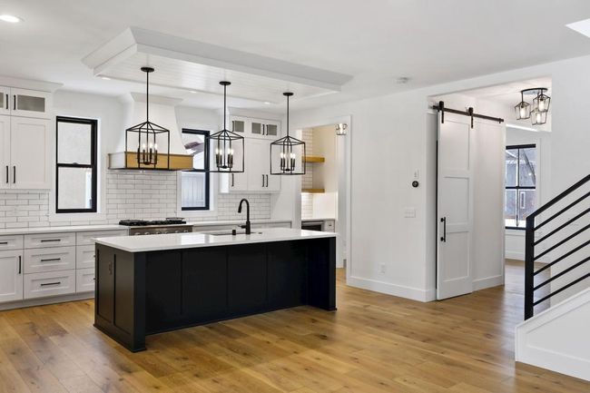 Modern kitchen with large central island, professional style appliances, quartz countertops, and custom cabinetry will please any chef. Pictures of previously built house. | Image 9