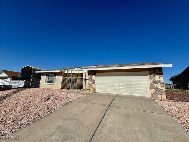 Ranch-style house featuring stone siding, concrete driveway, and a garage | Image 13