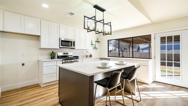 Kitchen with white cabinets, visible vents, decorative backsplash, and appliances with stainless steel finishes | Image 10
