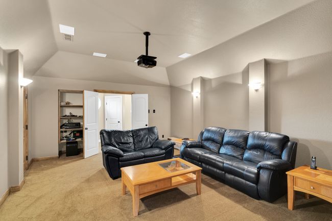 Living room or media room featuring light colored carpet and lofted ceiling | Image 33