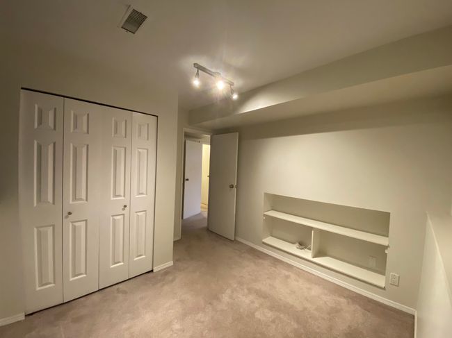 Unfurnished bedroom featuring a closet, track lighting, visible vents, carpet flooring, and baseboards | Image 14