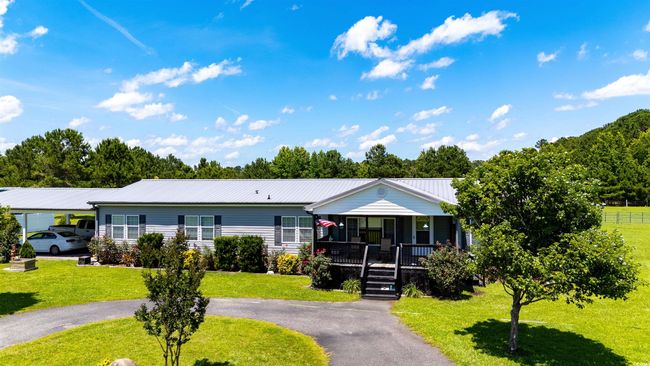 View of front facade with covered porch, a front lawn, a metal roof, and driveway | Image 39