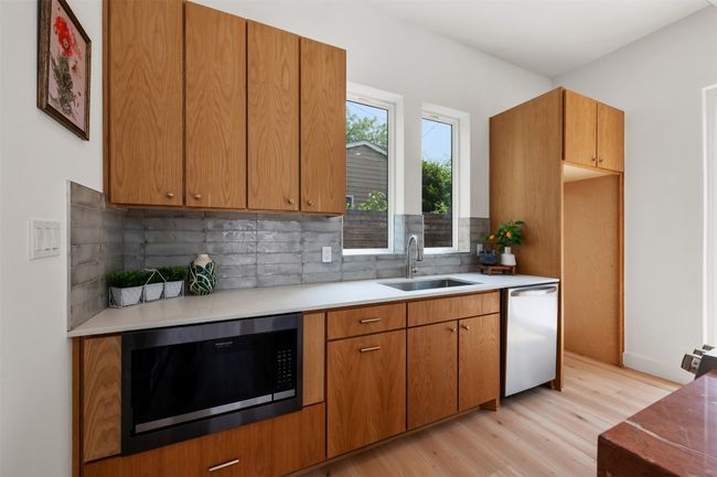 Kitchen with black microwave, a sink, dishwasher, light wood-type flooring, and tasteful backsplash | Image 8