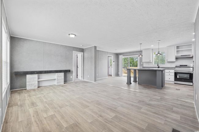 Unfurnished living room featuring a textured ceiling and light wood finished floors | Image 10