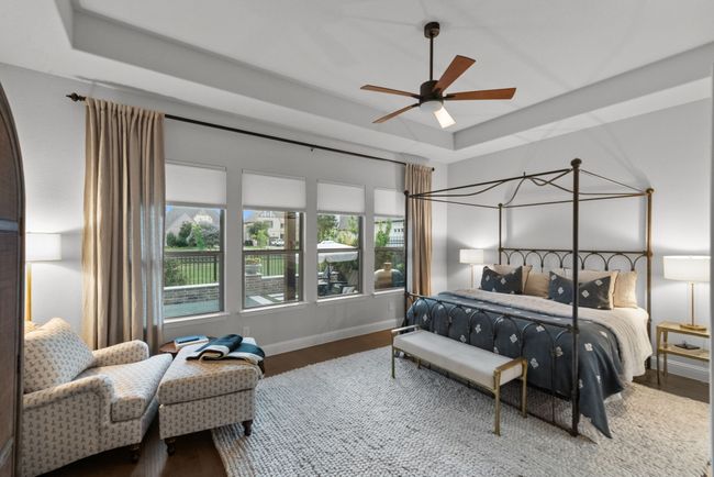 Primary bedroom with wall of windows, a tray ceiling, wood floors, and a ceiling fan | Image 19