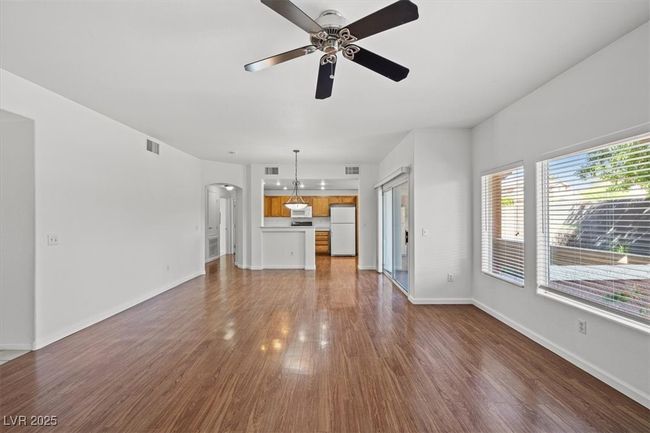 Unfurnished living room with baseboards, arched walkways, a ceiling fan, and wood finished floors | Image 12