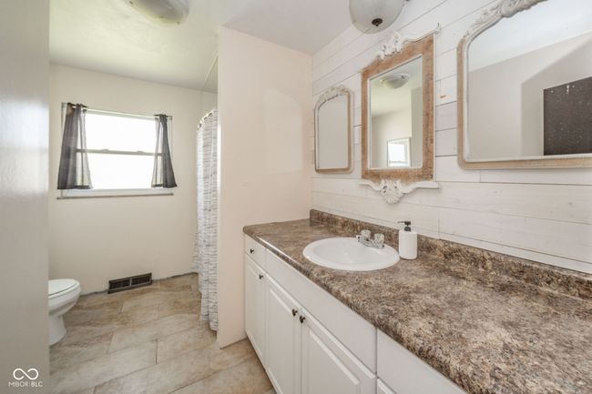 bathroom featuring toilet, wood walls, vanity, and visible vents | Image 6