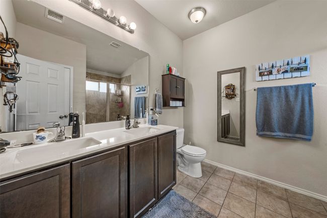Bathroom featuring a tile shower, double vanity, and tile patterned flooring | Image 13