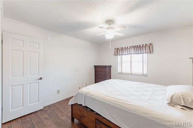 Bedroom featuring dark wood-style floors, ornamental molding, a textured ceiling, and a ceiling fan | Image 42